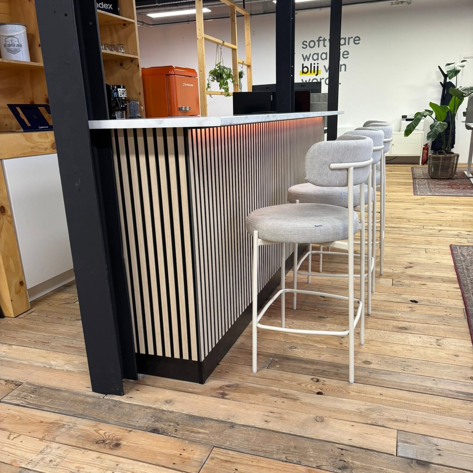 Dezelfde bar vanaf de kantoorzijde, met koffiehoek en de wand van de klant erachter